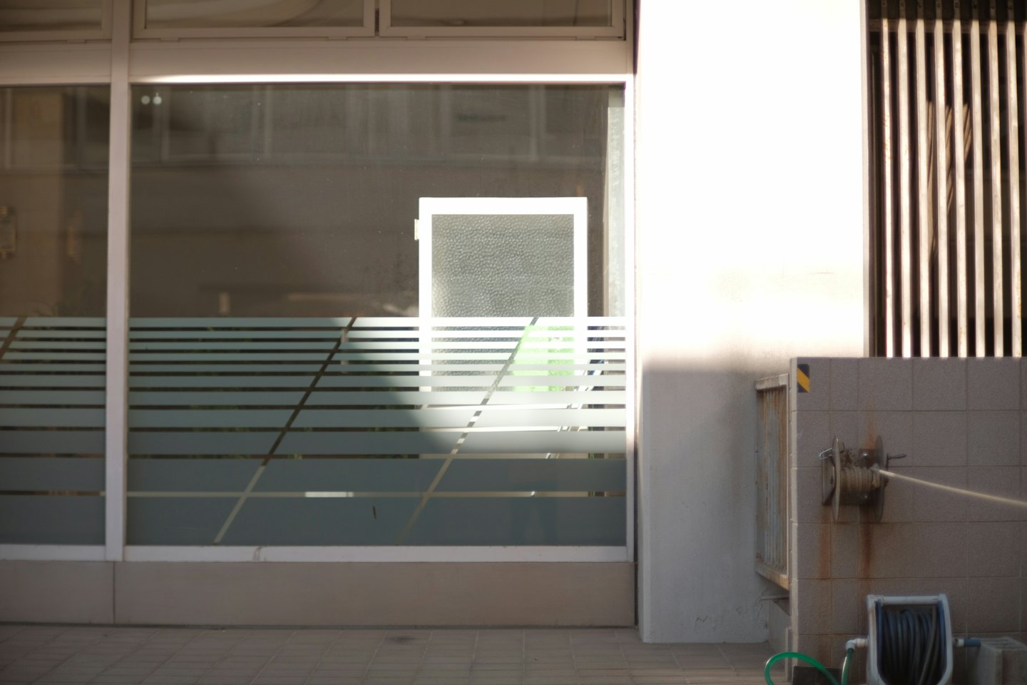 Modern building exterior with frosted glass windows and a green hose.